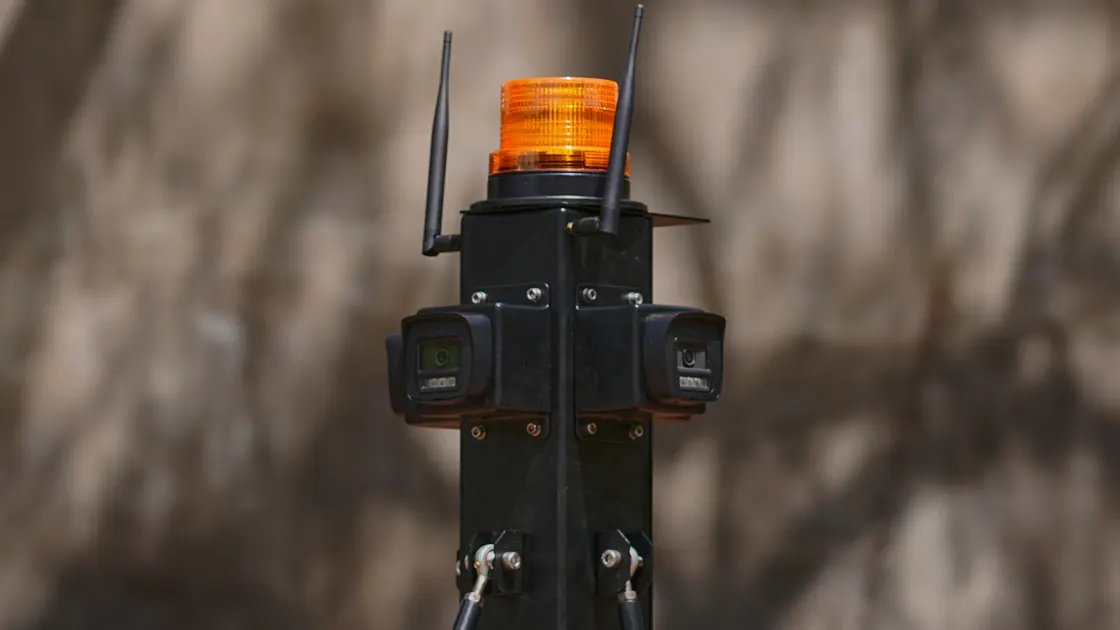 The sensor head on a Saibya mast in the field: a camera housing on each side, the radio antennas, and the amber warning beacon above them.